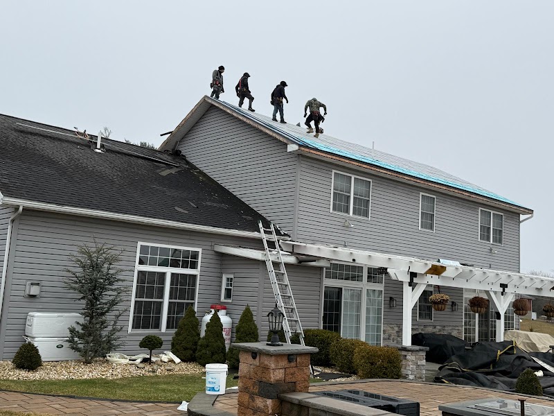 Roofing crew working along a grey home roofline.